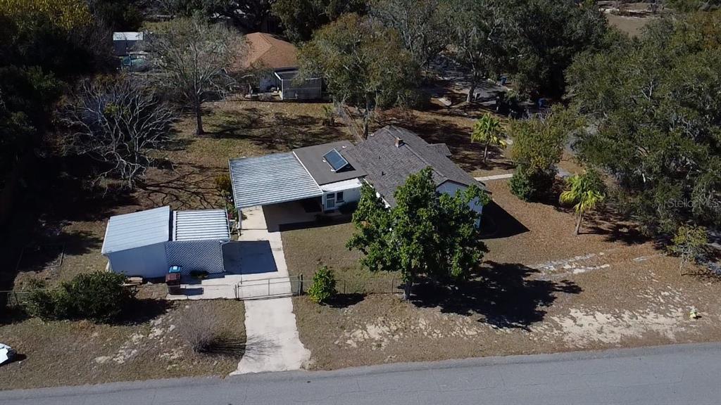 An aerial view shows a single-story house with a metal carport and a detached shed — 1240 DRUID CIRCLE, LAKE WALES, FL