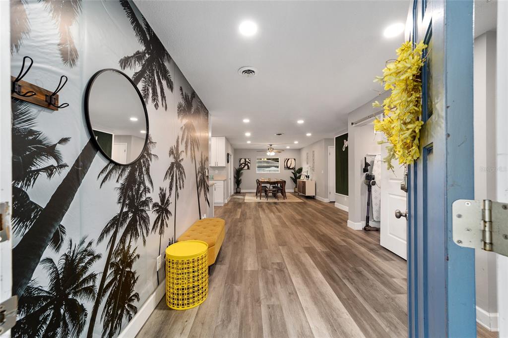 An entryway with palm tree wallpaper leads into an open-concept dining area with wood flooring — 3823 SE 9TH PLACE, OCALA, FL