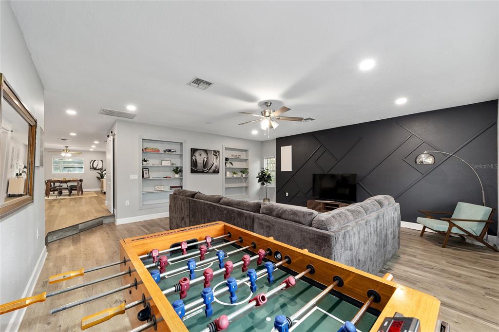 A living room features a foosball table, a large sectional sofa, and a dark accent wall — 3823 SE 9TH PLACE, OCALA, FL