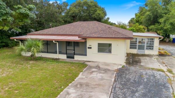 A single-story house with a brown shingled roof, a screened porch, and a concrete driveway — 1404 E ALFRED STREET, TAVARES, FL