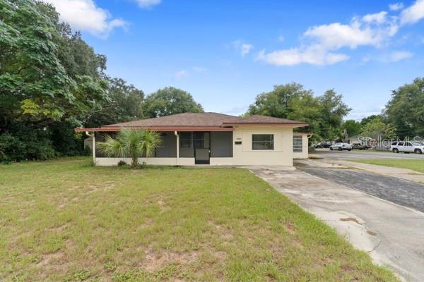A single-story house with a screened-in front porch and a concrete driveway — 1404 E ALFRED STREET, TAVARES, FL