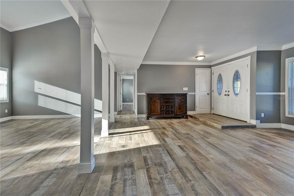 An open-concept living area features gray walls, wood-look flooring, white columns, and a front entryway — 1879 KAMLER AVENUE, ORLANDO, FL