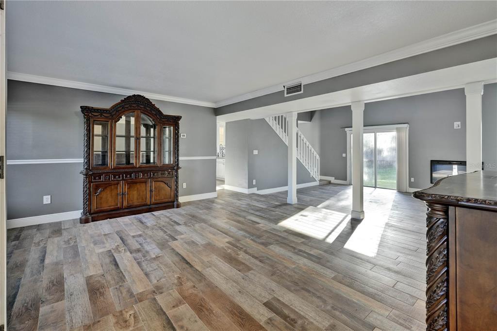 A living area features gray walls, wood-look tile flooring, a large hutch, and a staircase — 1879 KAMLER AVENUE, ORLANDO, FL