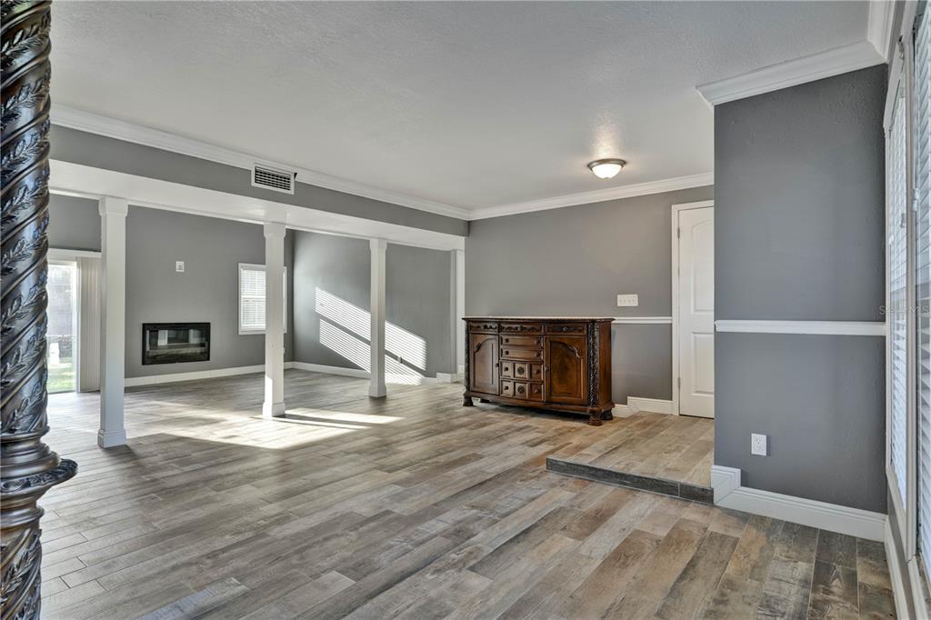 A living area with gray walls, wood-look tile flooring, white columns, and a wooden sideboard — 1879 KAMLER AVENUE, ORLANDO, FL