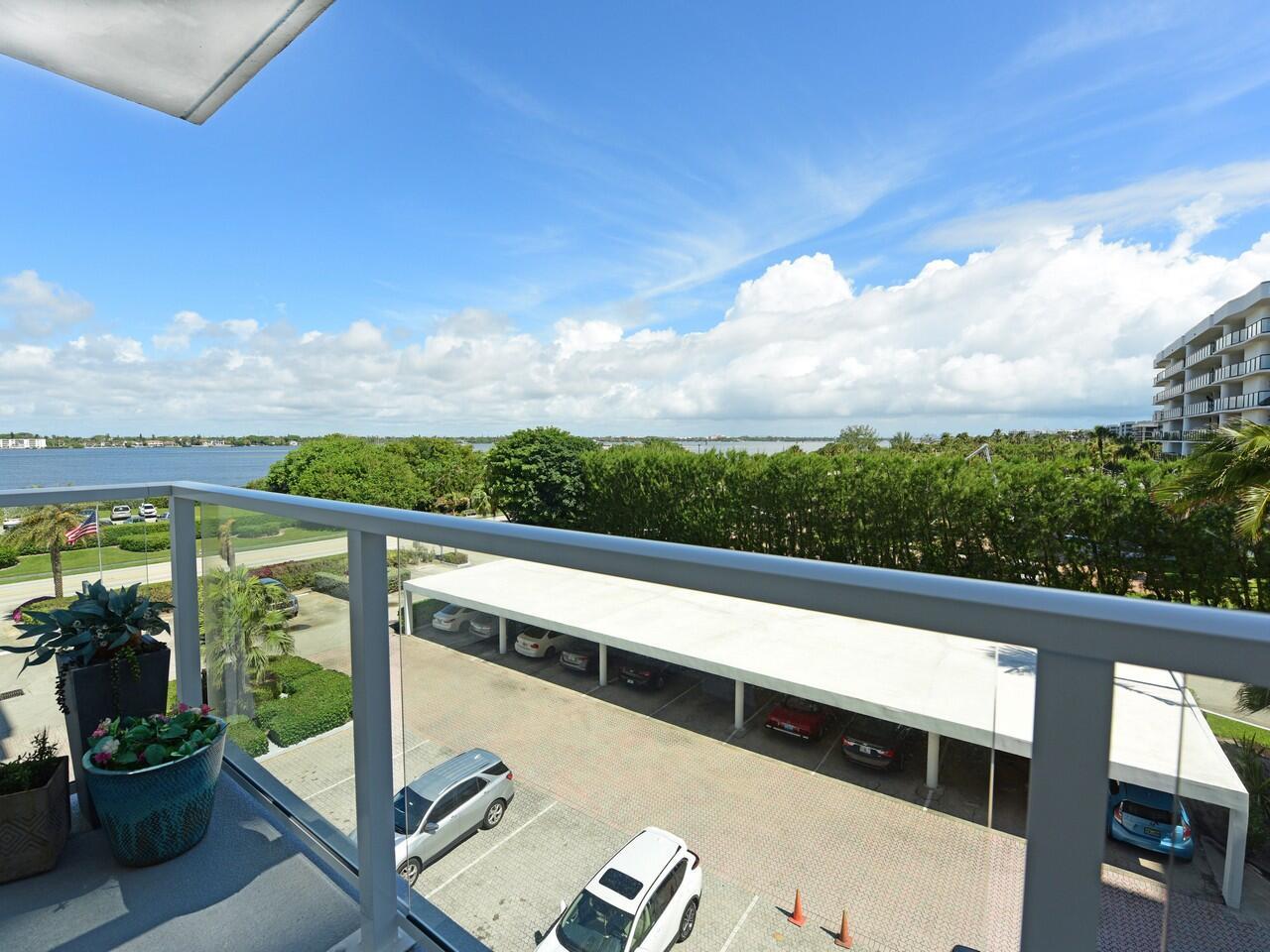 A high-angle view from a balcony overlooking a parking lot, trees, and a body of water — 3450 S Ocean Boulevard # 324, Palm Beach FL 33480, PALM BEACH, FL