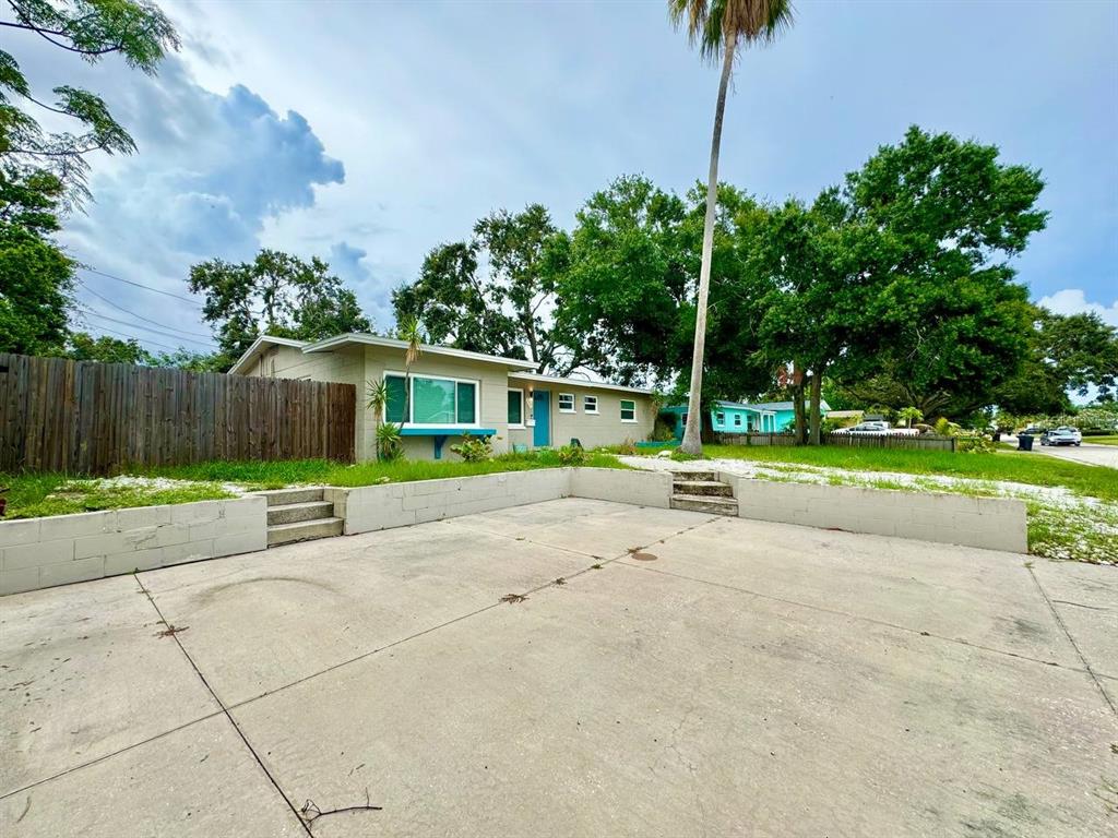 A concrete driveway leads to a single-story house with a retaining wall and palm tree — 3957 WAHOO DRIVE SE, ST PETERSBURG, FL