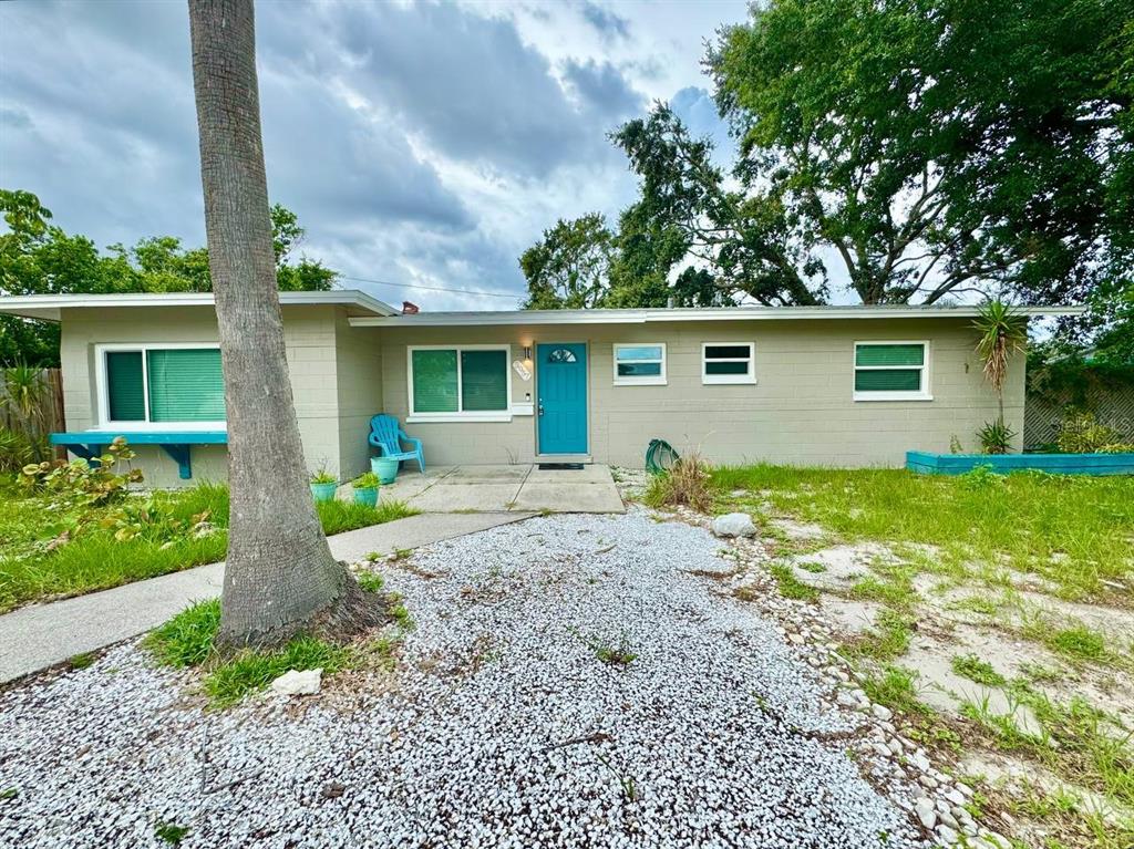 A single-story house with a teal front door, light-colored block walls, and a gravel yard — 3957 WAHOO DRIVE SE, ST PETERSBURG, FL