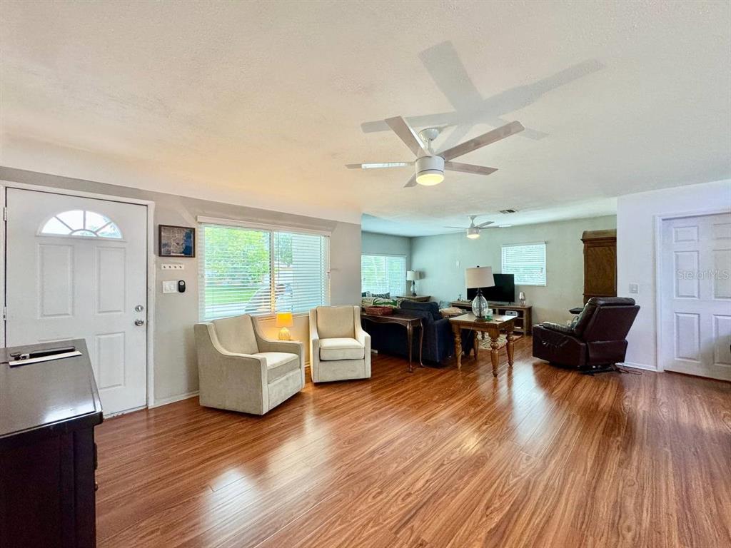 A living room with hardwood floors, two armchairs, a sofa, and a ceiling fan — 3957 WAHOO DRIVE SE, ST PETERSBURG, FL