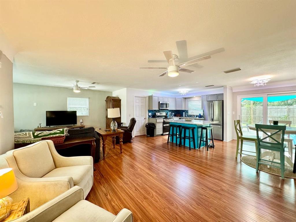 An open-concept living room and kitchen featuring wood-look flooring and a central island — 3957 WAHOO DRIVE SE, ST PETERSBURG, FL