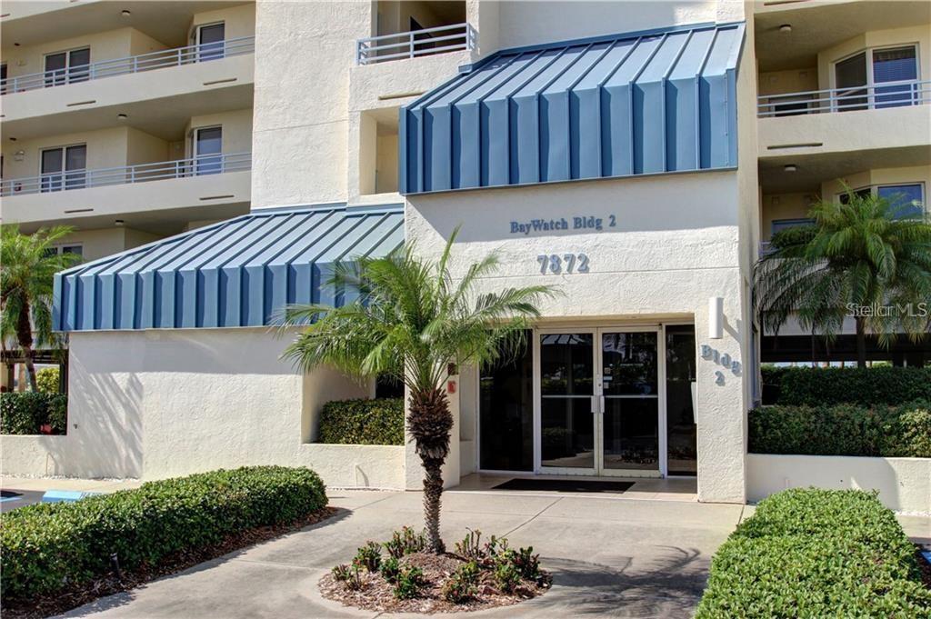 The exterior entrance of a multi-story apartment building features a blue metal awning — 7872 SAILBOAT KEY BOULEVARD S UNIT PH602, SOUTH PASADENA, FL