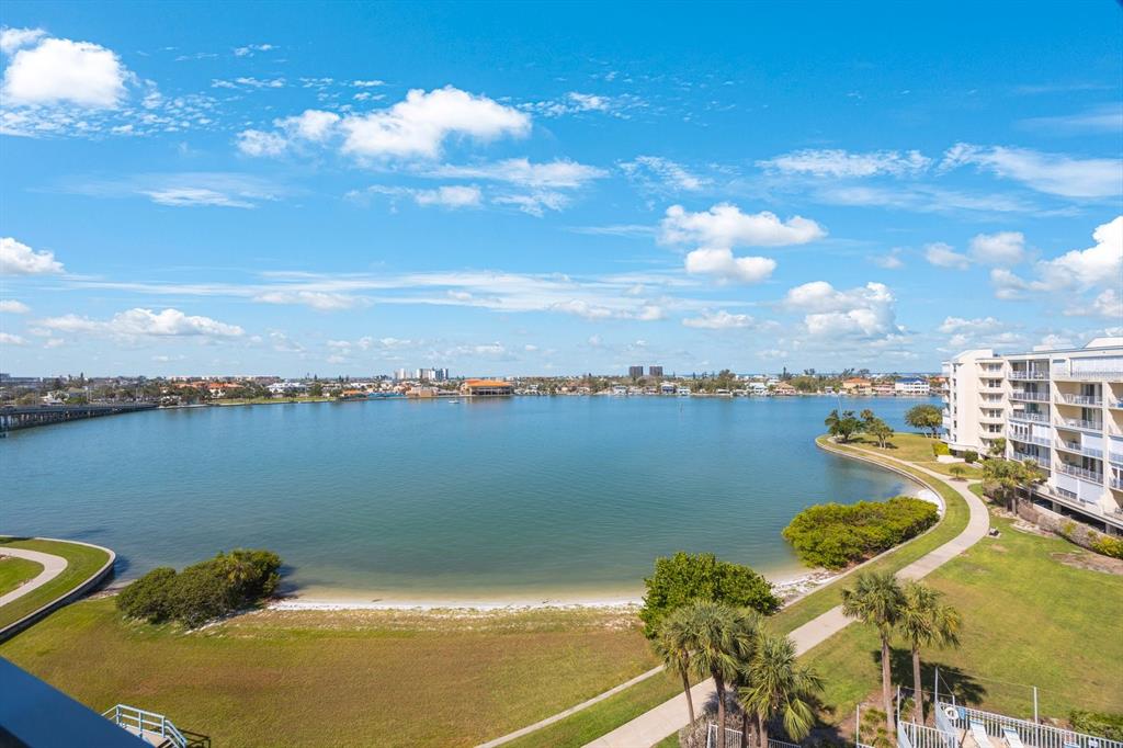 An elevated view of a bay with a sandy shoreline, grassy park, and apartment buildings — 7872 SAILBOAT KEY BOULEVARD S UNIT PH602, SOUTH PASADENA, FL