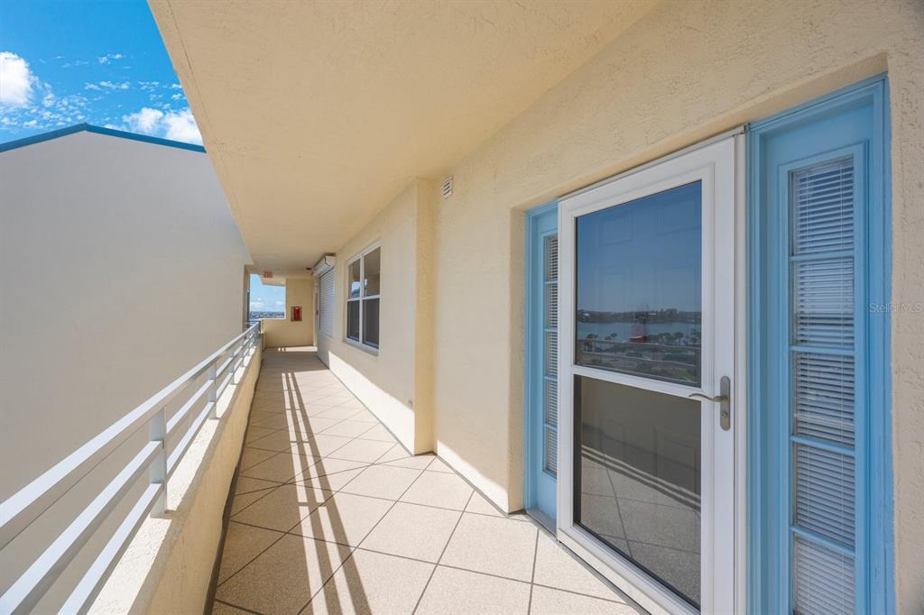 An outdoor balcony with a tiled floor, white railings, and a blue-framed glass door — 7872 SAILBOAT KEY BOULEVARD S UNIT PH602, SOUTH PASADENA, FL