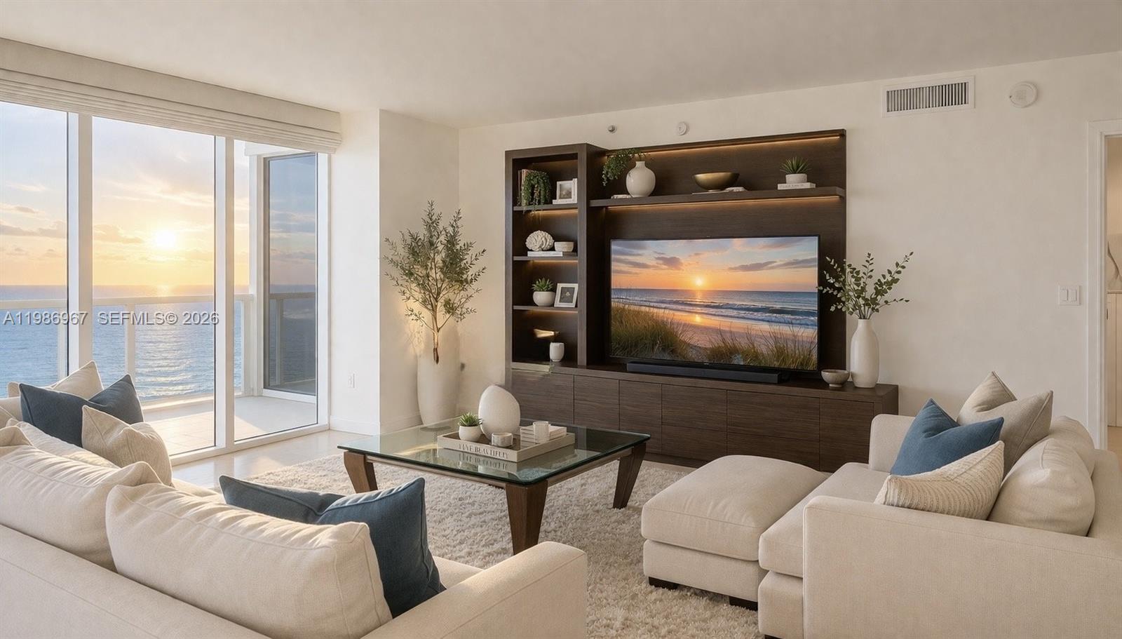A living room features a large entertainment unit, cream sofas, and a balcony with ocean views — 1800 S Ocean Dr, Hallandale Beach FL 33009, HALLANDALE BEACH, FL
