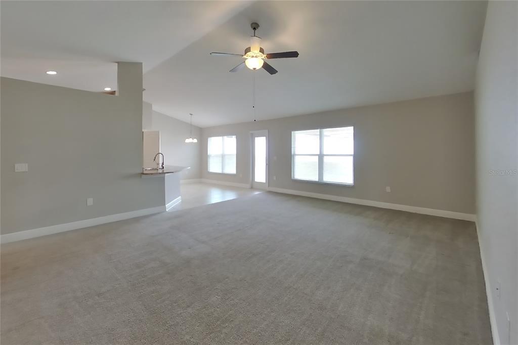 A spacious living room features neutral carpet, light gray walls, and a ceiling fan — 1599 LEMON AVENUE, WINTER HAVEN, FL