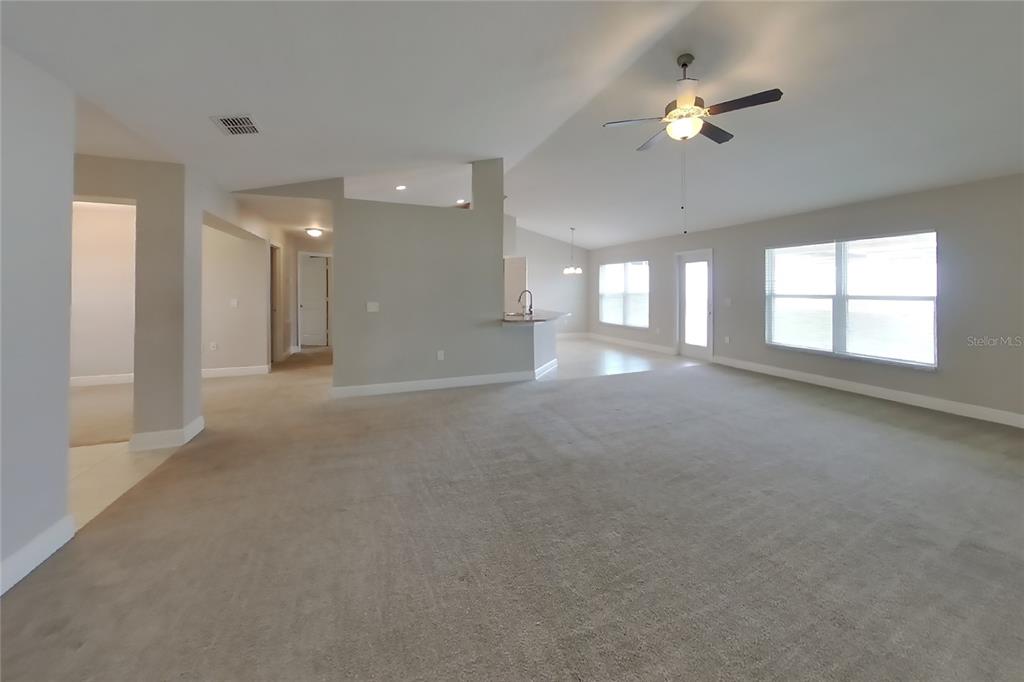 A spacious living room features neutral carpeting, light gray walls, and a ceiling fan — 1599 LEMON AVENUE, WINTER HAVEN, FL