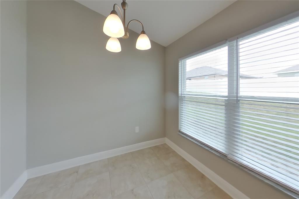 A small dining area with light-colored tile flooring, gray walls, and a three-light chandelier — 1599 LEMON AVENUE, WINTER HAVEN, FL