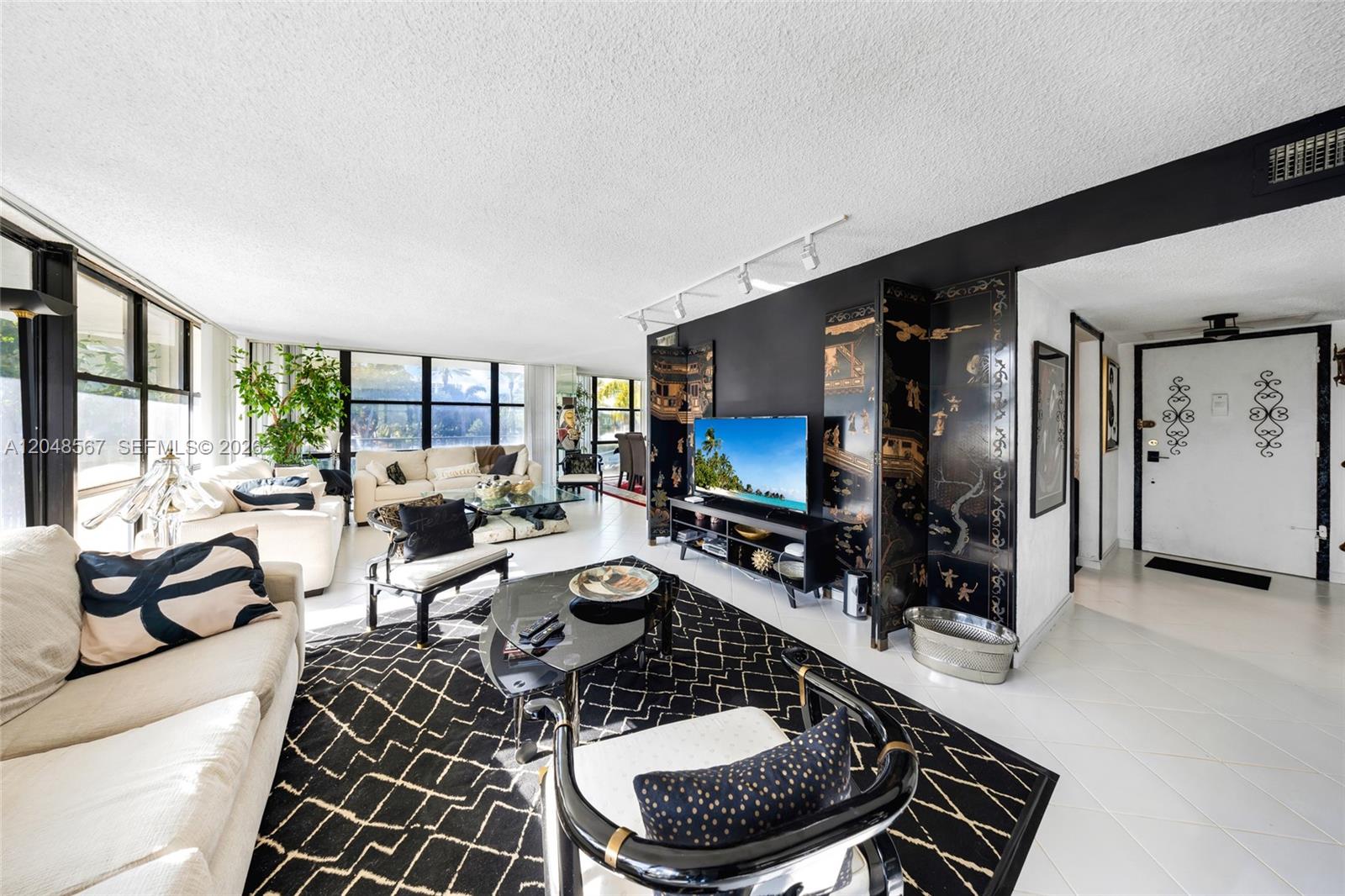 A living room features a black accent wall, a patterned rug, and floor-to-ceiling windows — 800 Parkview Dr # 230, Hallandale Beach FL 33009, HALLANDALE BEACH, FL