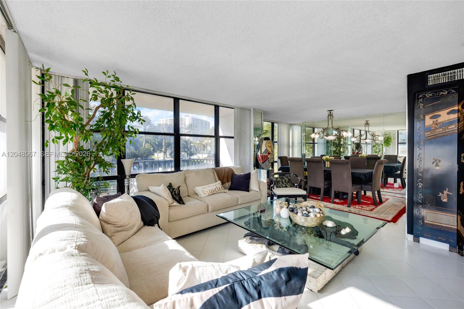 A living and dining area features white tile floors, a glass coffee table, and windows — 800 Parkview Dr # 230, Hallandale Beach FL 33009, HALLANDALE BEACH, FL
