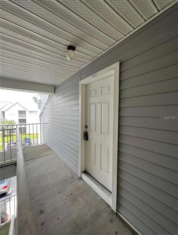 An exterior view shows a white apartment door numbered 303 on a concrete walkway — 1226 BERMUDA LAKES LANE UNIT 303, KISSIMMEE, FL