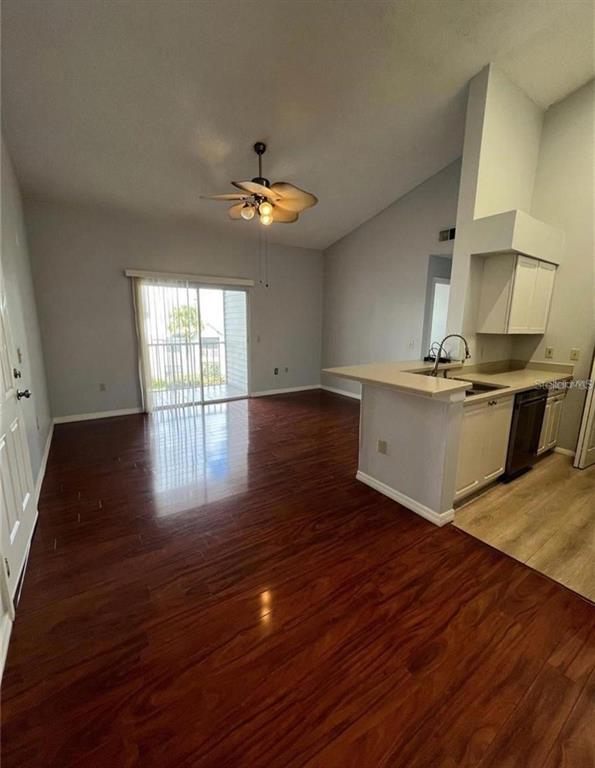 A living room with hardwood floors and a ceiling fan connects to an open kitchen — 1226 BERMUDA LAKES LANE UNIT 303, KISSIMMEE, FL