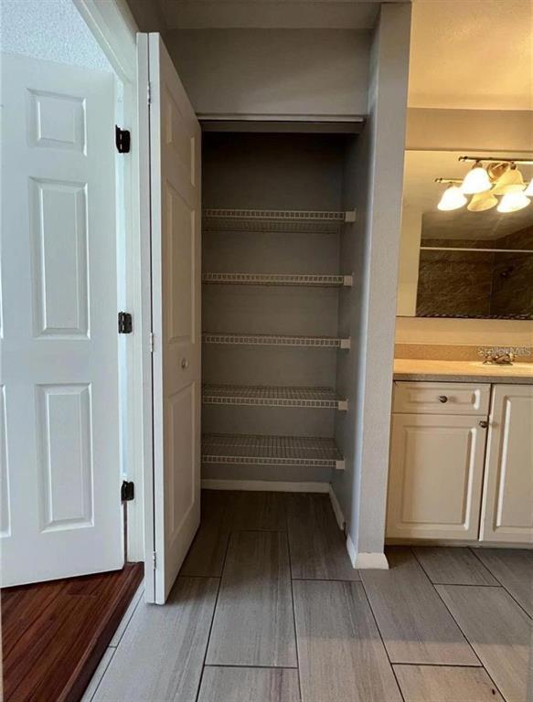A bathroom features a white door, an open linen closet with wire shelving, and cabinetry — 1226 BERMUDA LAKES LANE UNIT 303, KISSIMMEE, FL