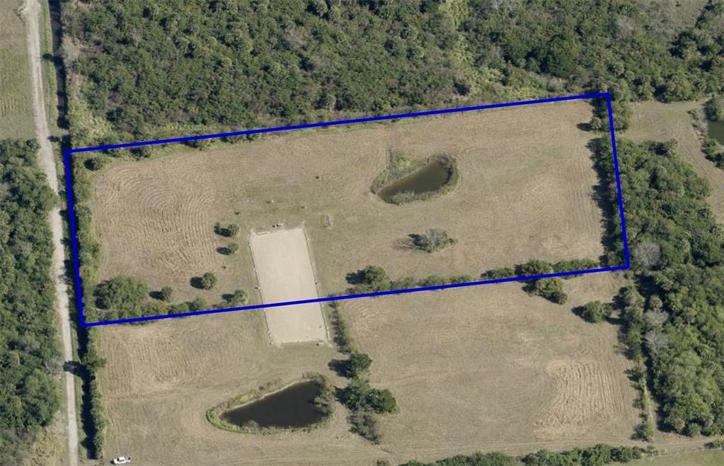 An aerial view shows a rectangular plot of land featuring a riding arena and pond — 0 ORLANDO AVENUE, MIMS, FL