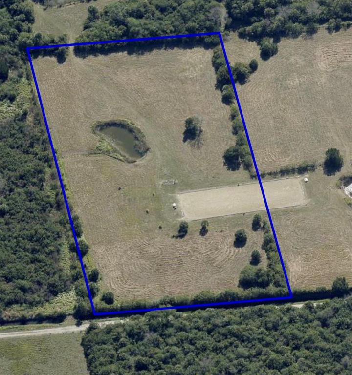 An aerial view shows a rectangular plot of land featuring a pond and riding arena — 0 ORLANDO AVENUE, MIMS, FL