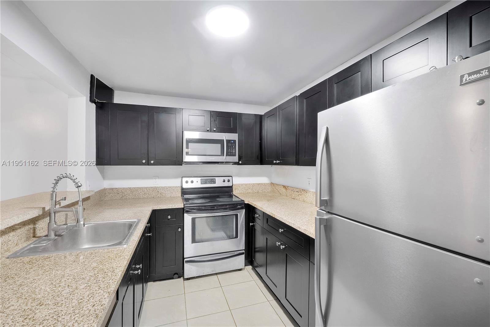 A kitchen features dark cabinets, stainless steel appliances, and speckled granite countertops — 4221 NW 19th St # 289, Lauderhill FL 33313, LAUDERHILL, FL