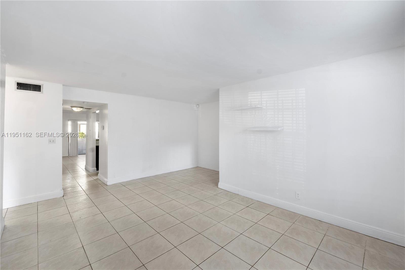 An empty room features white walls, beige tile flooring, and two small wall-mounted shelves — 4221 NW 19th St # 289, Lauderhill FL 33313, LAUDERHILL, FL