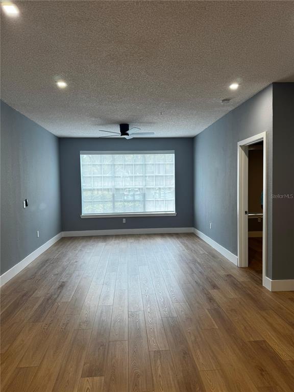 A room with gray walls, wood-look flooring, a ceiling fan, and a large window — 13001 MULBERRY PARK DR UNIT 112, ORLANDO, FL