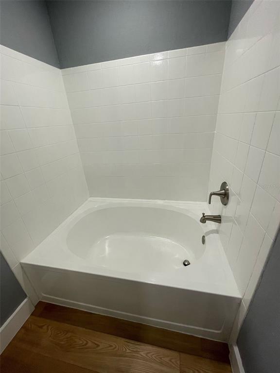 A white soaking tub is surrounded by white square wall tiles and dark gray walls — 13001 MULBERRY PARK DR UNIT 112, ORLANDO, FL