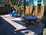 A paved backyard patio features a dining set and two blue Adirondack chairs — 2802 PASS A GRILLE WAY UNIT 2, ST PETERSBURG, FL