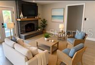 A living room features a stone fireplace, a light-colored sofa, and two wicker armchairs — 2802 PASS A GRILLE WAY UNIT 2, ST PETERSBURG, FL