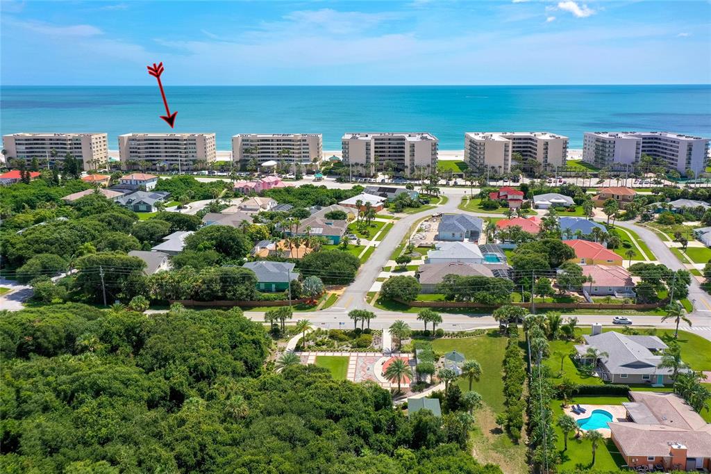 An aerial view shows several beachfront apartment buildings situated behind a residential neighborhood and trees — 4535 S ATLANTIC AVENUE UNIT 2701, PORT ORANGE, FL