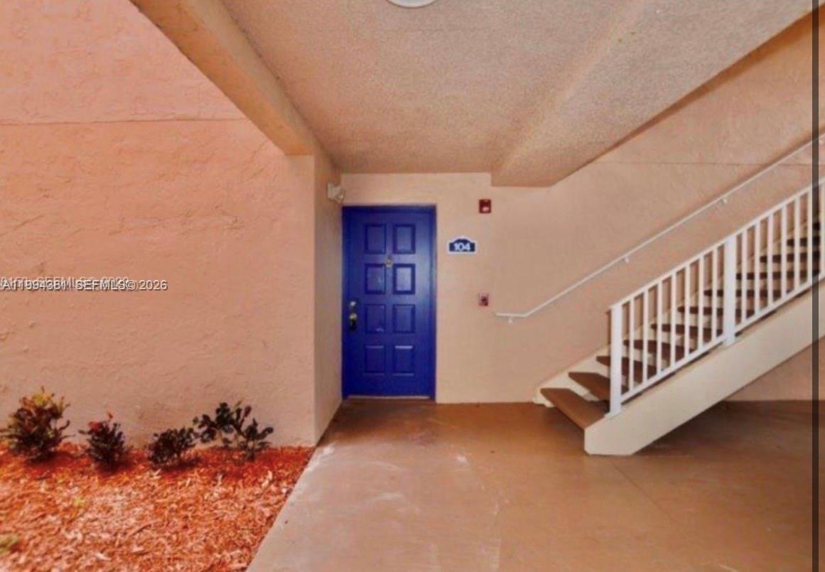 A blue front door is located under a covered walkway next to an outdoor staircase — 10630 SW 158th Ct # 104, Miami FL 33196, MIAMI, FL