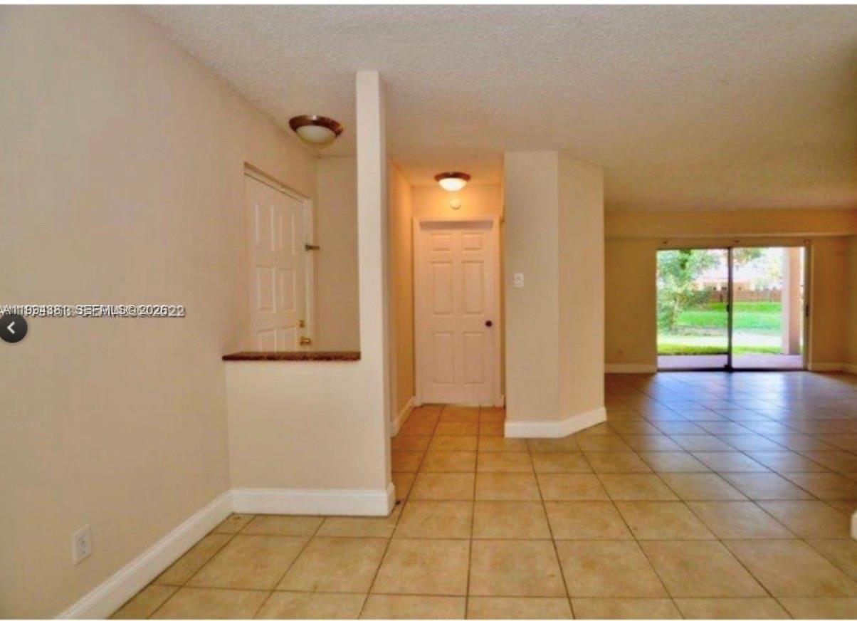 An interior view showing a tiled entryway, a white door, and a living area beyond — 10630 SW 158th Ct # 104, Miami FL 33196, MIAMI, FL