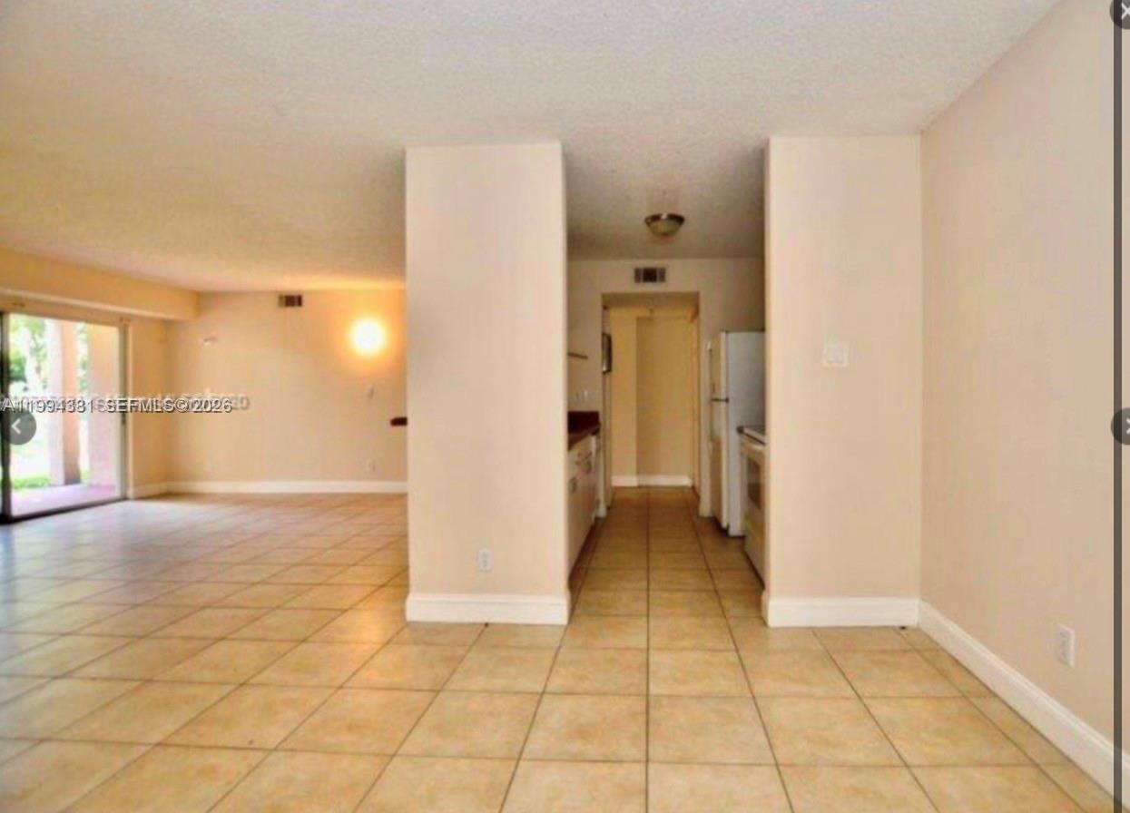 A tiled floor leads from a dining area into a narrow kitchen with white appliances — 10630 SW 158th Ct # 104, Miami FL 33196, MIAMI, FL