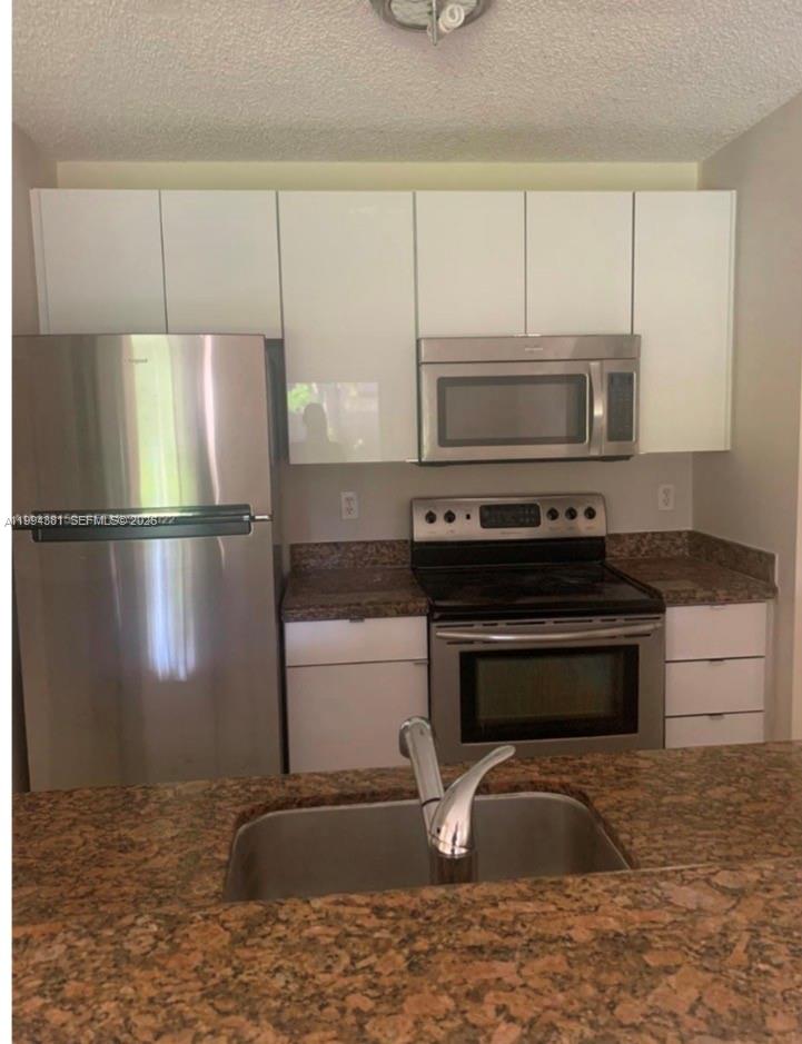 A kitchen features stainless steel appliances, white upper cabinets, and brown granite countertops — 10630 SW 158th Ct # 104, Miami FL 33196, MIAMI, FL