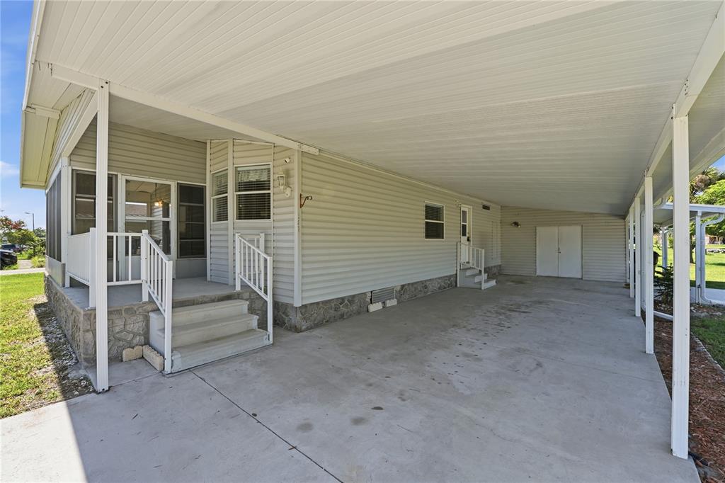 A side view of a manufactured home featuring a large concrete carport and screened porch — 2251 TEMPLE LANE, ST CLOUD, FL