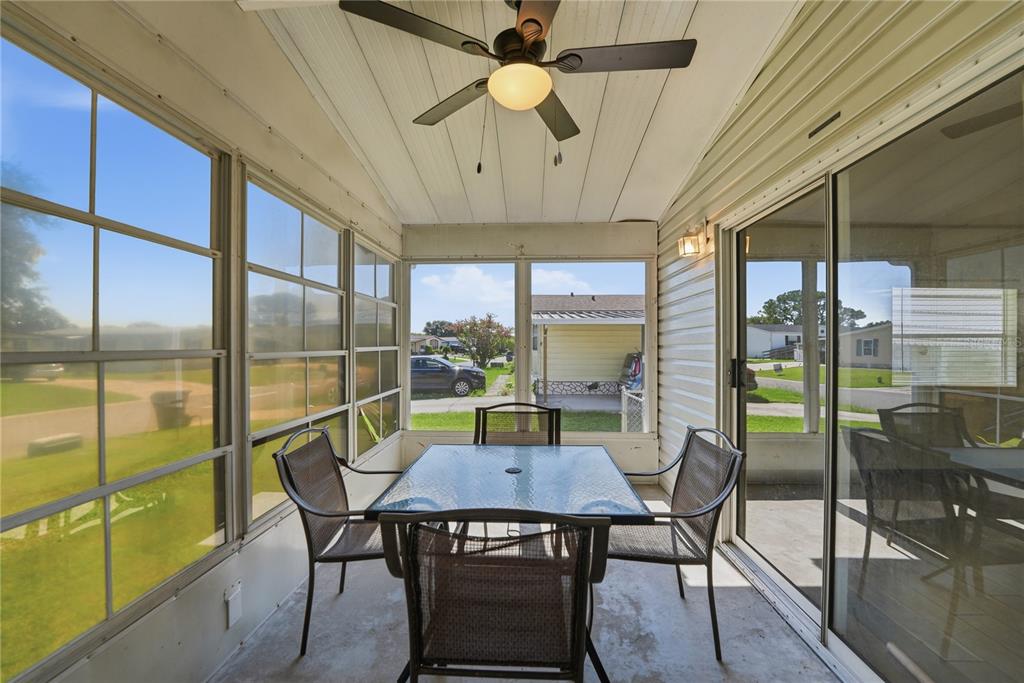 A screened-in porch features a glass-top dining table, four chairs, and a ceiling fan — 2251 TEMPLE LANE, ST CLOUD, FL