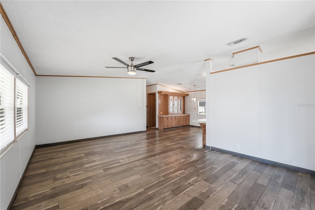 An open living area features wood-look flooring, white walls, and a ceiling fan — 2251 TEMPLE LANE, ST CLOUD, FL