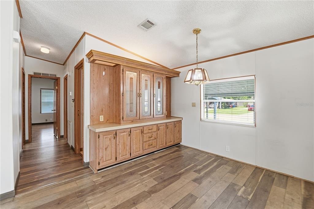 A dining area features wood-look flooring, a built-in hutch, and a hanging light fixture — 2251 TEMPLE LANE, ST CLOUD, FL