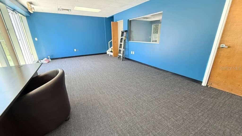 An office space features blue walls, gray carpeting, a desk, and a windowed partition — 4333 SILVER STAR ROAD UNIT 17, ORLANDO, FL