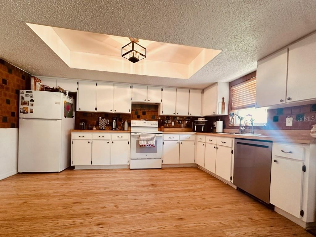 A kitchen with white cabinets, a white stove, a stainless steel dishwasher, and wood-look flooring — 1831 KIM ACRES LANE, DOVER, FL