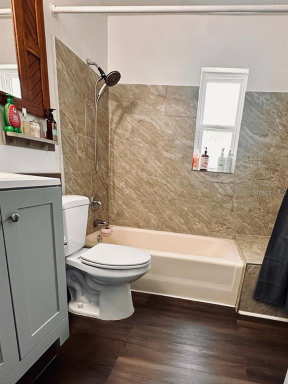 A bathroom features a light-colored bathtub, a toilet, and a vanity with wood-look flooring — 1831 KIM ACRES LANE, DOVER, FL
