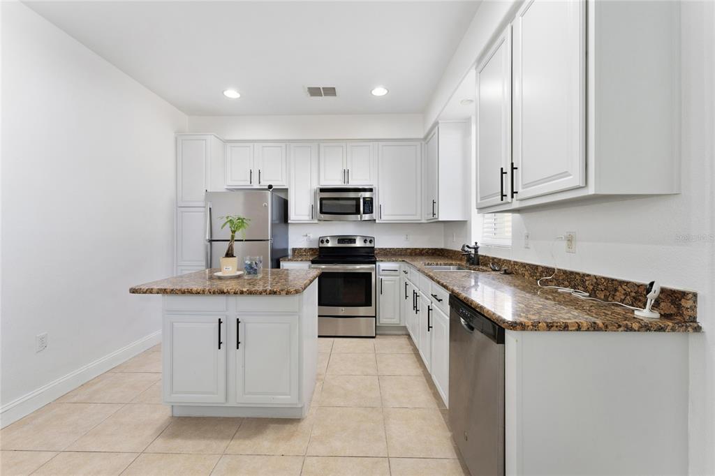 A kitchen features white cabinets, granite countertops, stainless steel appliances, and a central island — 2616 BELLA VISTA DRIVE, DAVENPORT, FL