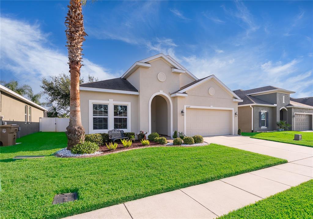 A single-story suburban house with a beige stucco exterior, a two-car garage, and a palm tree — 2587 TANNER TERRACE, KISSIMMEE, FL