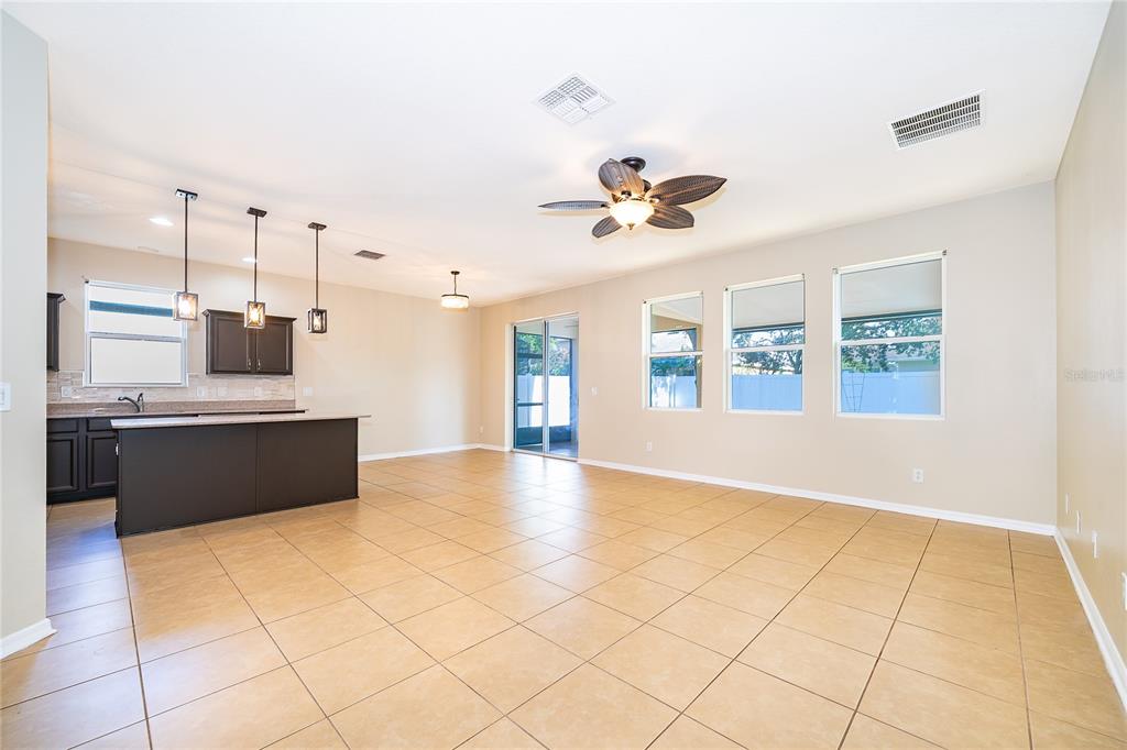 An open-concept kitchen and living area features tile flooring, dark cabinetry, and a ceiling fan — 2587 TANNER TERRACE, KISSIMMEE, FL