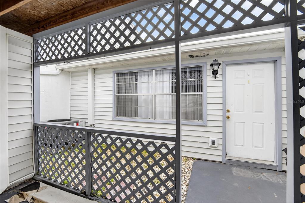 A white exterior wall features a window, a white door, and a lattice privacy screen — 11920 DIETZ DRIVE UNIT 11920, TAMPA, FL