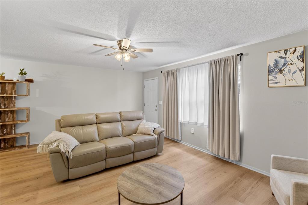 A living room features a beige leather sofa, a round coffee table, and wood flooring — 11920 DIETZ DRIVE UNIT 11920, TAMPA, FL